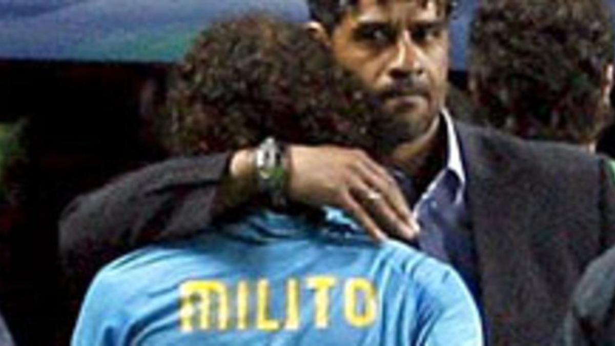 Rijkaard consuela a Milito tras la derrota del Barça en Manchester, el martes.