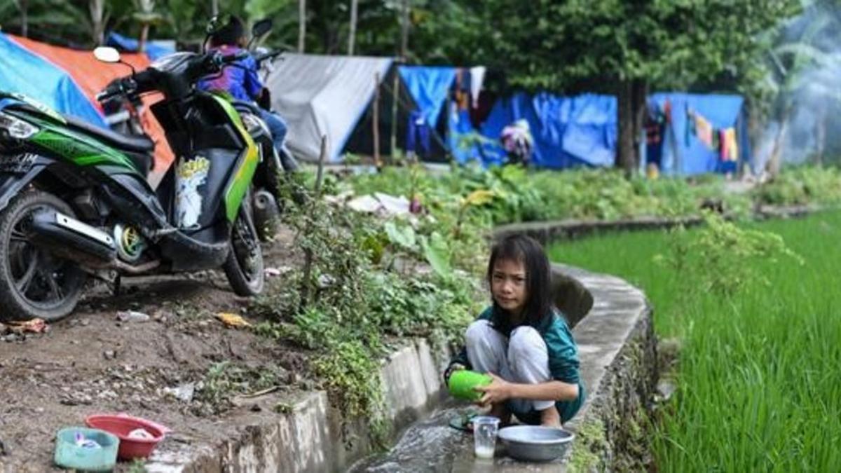 Una niña lava los platos en un campamento para desplazados por el tsunami en Rajabasa, en la provincia indonesia de Lampung.