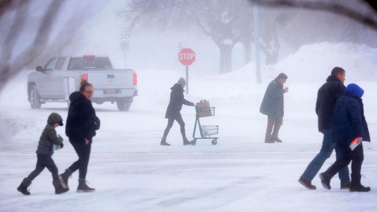 Paseantes caminan entre la nieve al salir de una tienda de comestibles