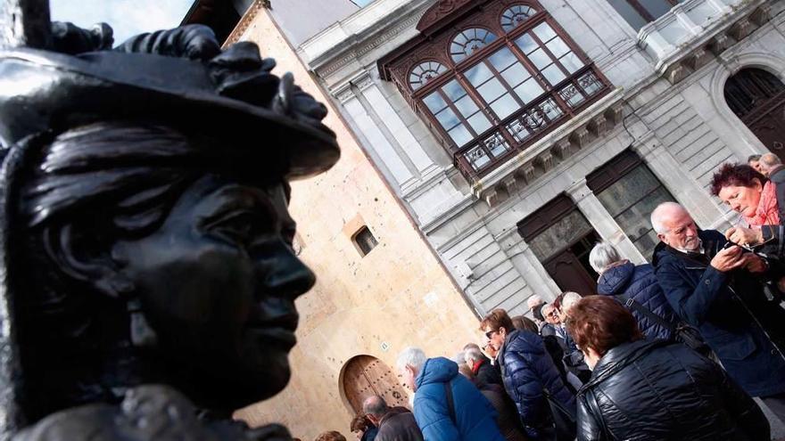 Turistas, ayer, en la plaza de la Catedral, en Oviedo, ante la estatua de la Regenta.