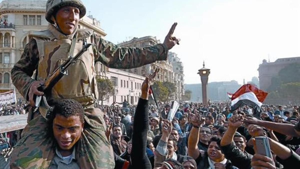 Un opositor aúpa a un soldado en la plaza Tahrir de El Cairo, ayer.