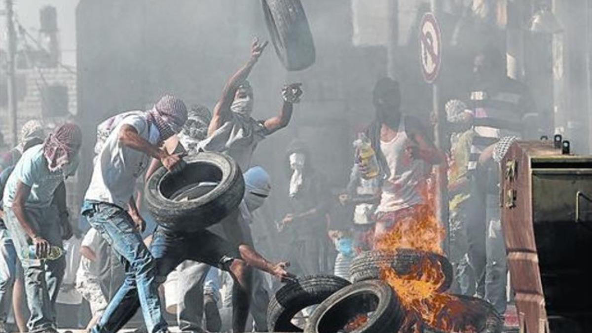 Unos jóvenes palestinos prenden fuego a unos neumáticos y se enfrentan a la policía, ayer, en el barrio de Shuafat, al este de Jerusalén.