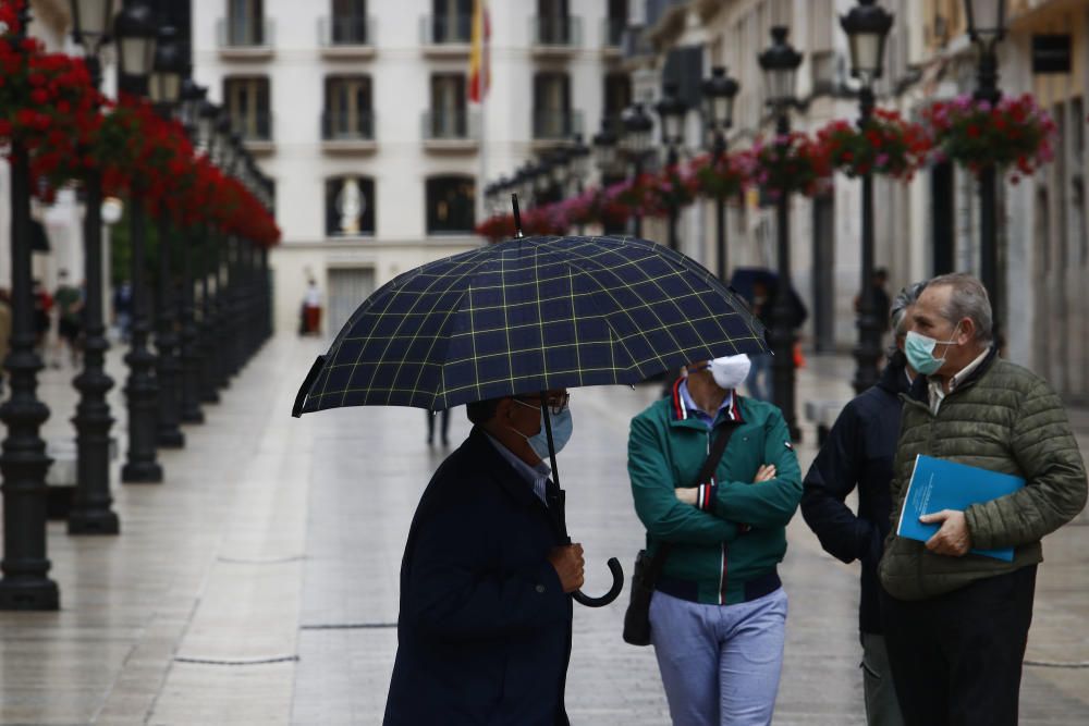 Imágenes de una lluviosa mañana de jueves en el centro de Málaga, donde al paisaje ya habitual de pocas personas y la mayoría de ellas con guantes y mascarillas se le han añadido los preparativos de bares, cafeterías y terrazas que se preparan para el inminente cambio de fase de la desescalada de la ciudad.