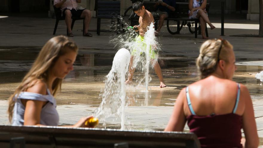 Un niño se refresca en una fuente en Alicante