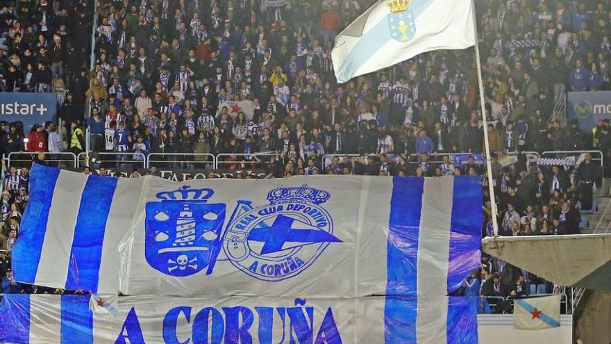 Aficionados blanquiazules muestran una pancarta con los escudos de A Coruña y el Deportivo, este con el topónimo oficial en gallego.
