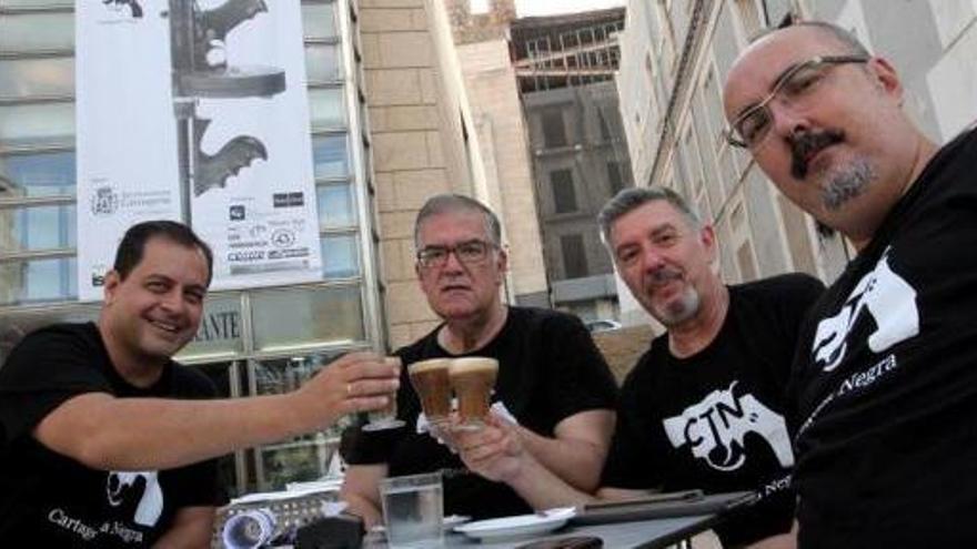 Los organizadores del festival Cartagena Negra, ayer, tras la instalación del cartel anunciador del certamen en el Teatro Romano.