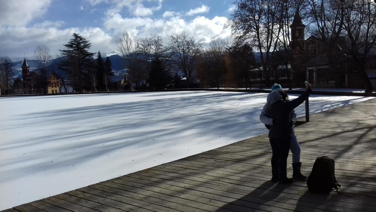 Dues persones es fotografien davant el llac de Puigcerdà, ben blanc