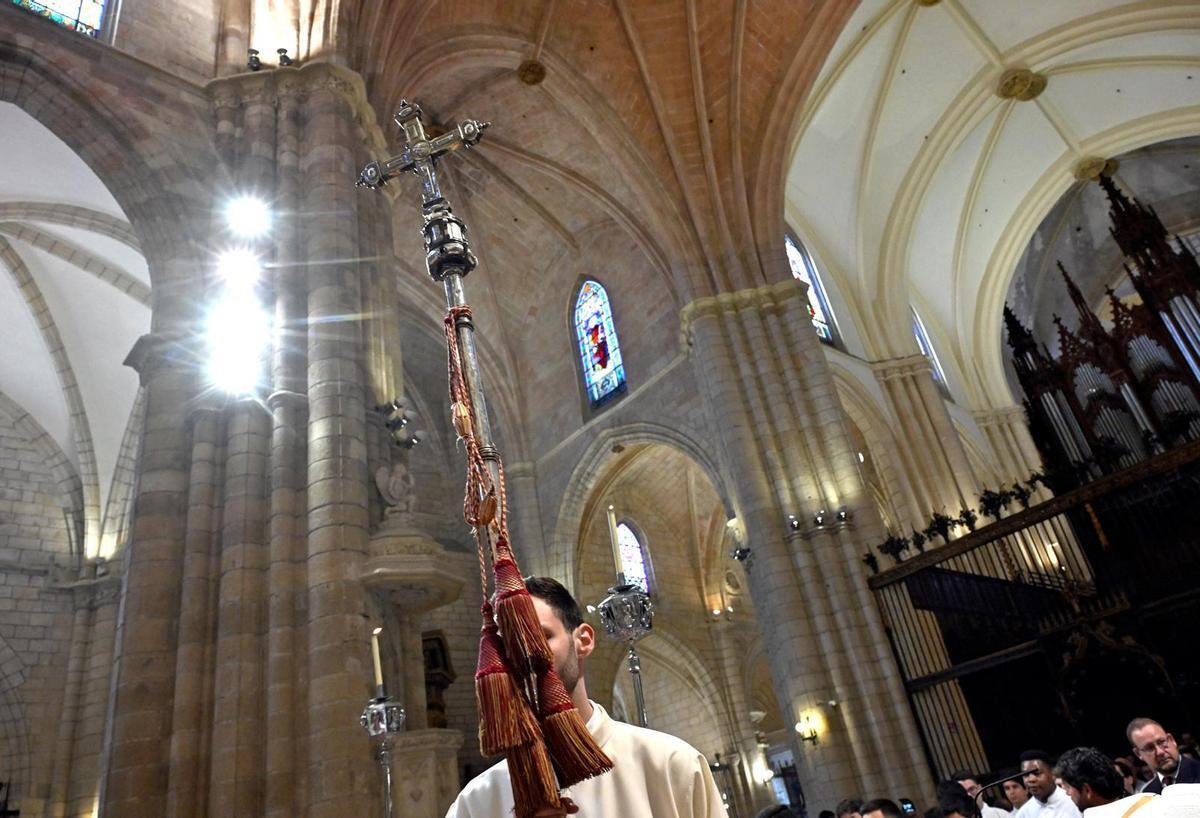 Un joven sostiene una cruz procesional en la Catedral de Murcia.
