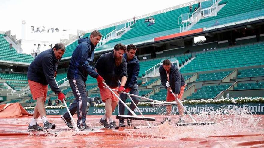 Los operarios sacan el agua de la pista central de Roland Garros. // Efe