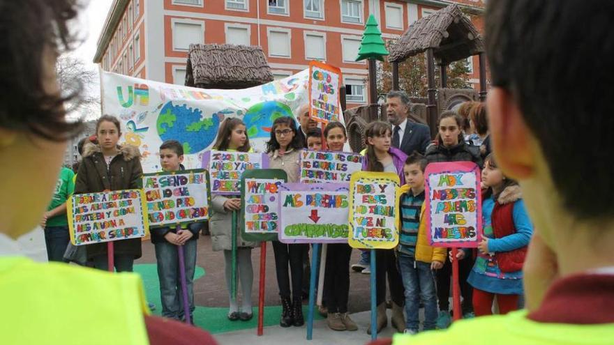 Raúl Blanco, Paula Fernández, Ainara Fernández y Alberto López, con el trabajo que realizaron en su colegio. A la derecha, varios niños durante la presentación del nuevo parque infantil.