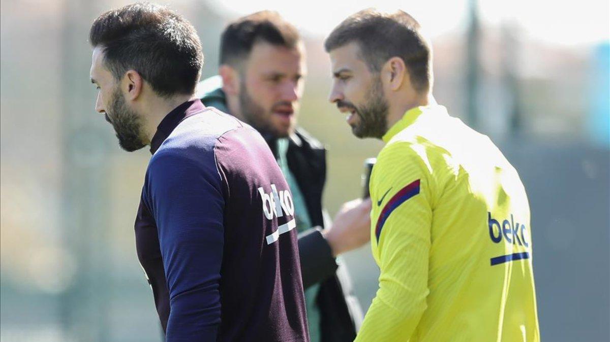 Sarabia y Piqué charlan mientras salen al campo de entrenamiento