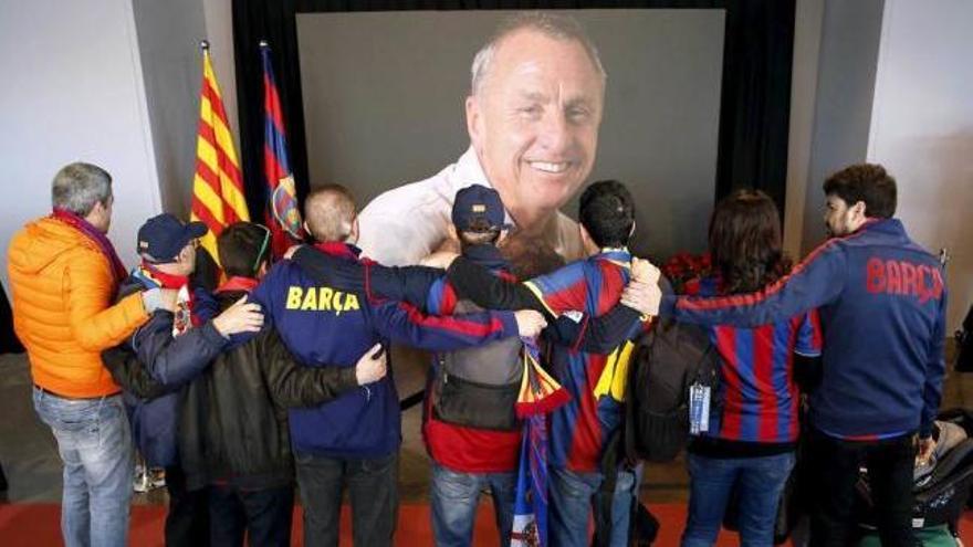 Un grupo de aficionados se abrazan ante una imagen de Cruyff.