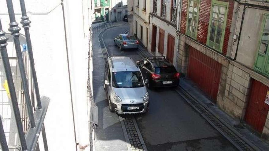 Un vehículo se sube a la acera para poder cruzarse con otro en la calle pixueta.