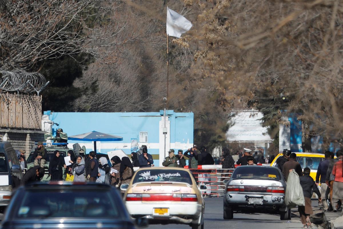 Mujeres afganas en la puerta de la universidad, custodiada por soldados, en Kabul.