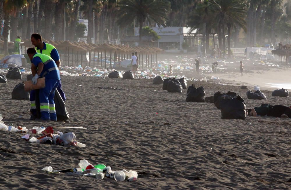 Los operarios de los servicios de limpieza trabajan para dejar la playa en óptimas condiciones tras una larga noche de fiesta en la arena