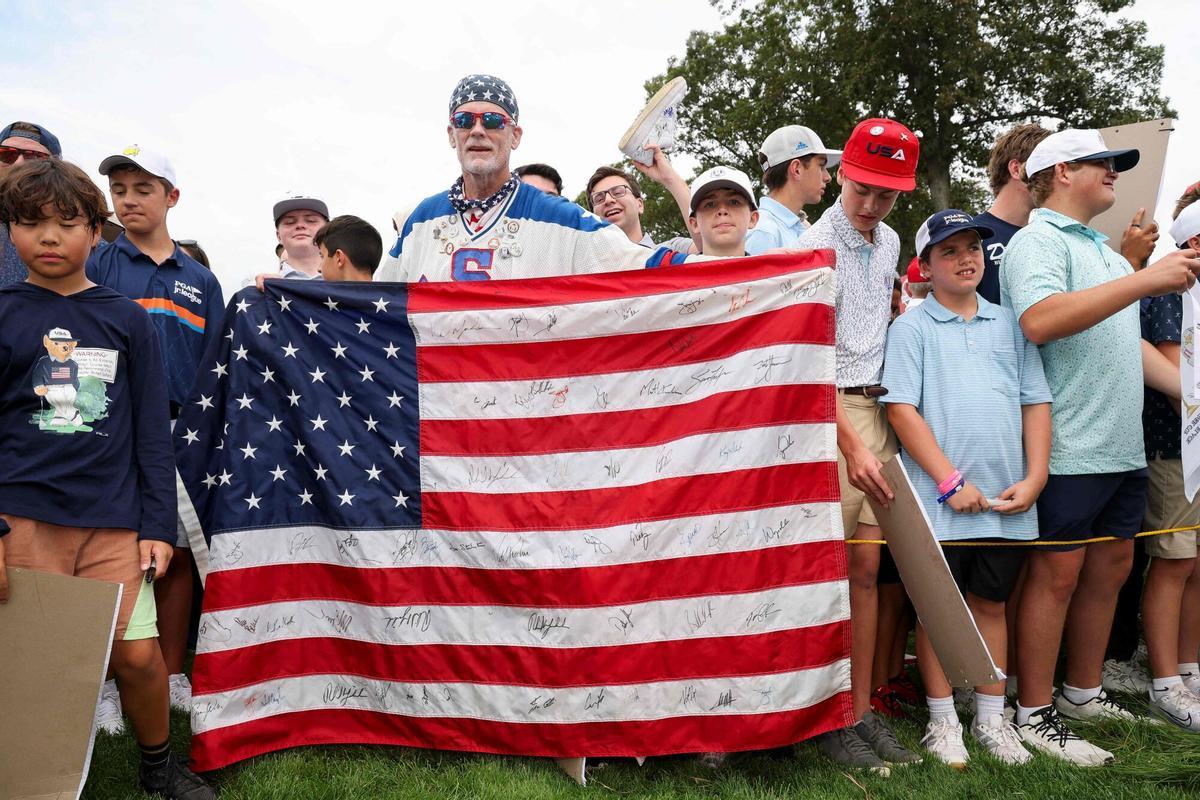 FARMINGDALE, NEW YORK - SEPTEMBER 24: A fan holds a United States flag during a practice round prior to the Ryder Cup 2025 at Black Course at Bethpage State Park Golf Course on September 24, 2025 in Farmingdale, New York. Jamie Squire/Getty Images/AFP (Photo by JAMIE SQUIRE / GETTY IMAGES NORTH AMERICA / Getty Images via AFP)