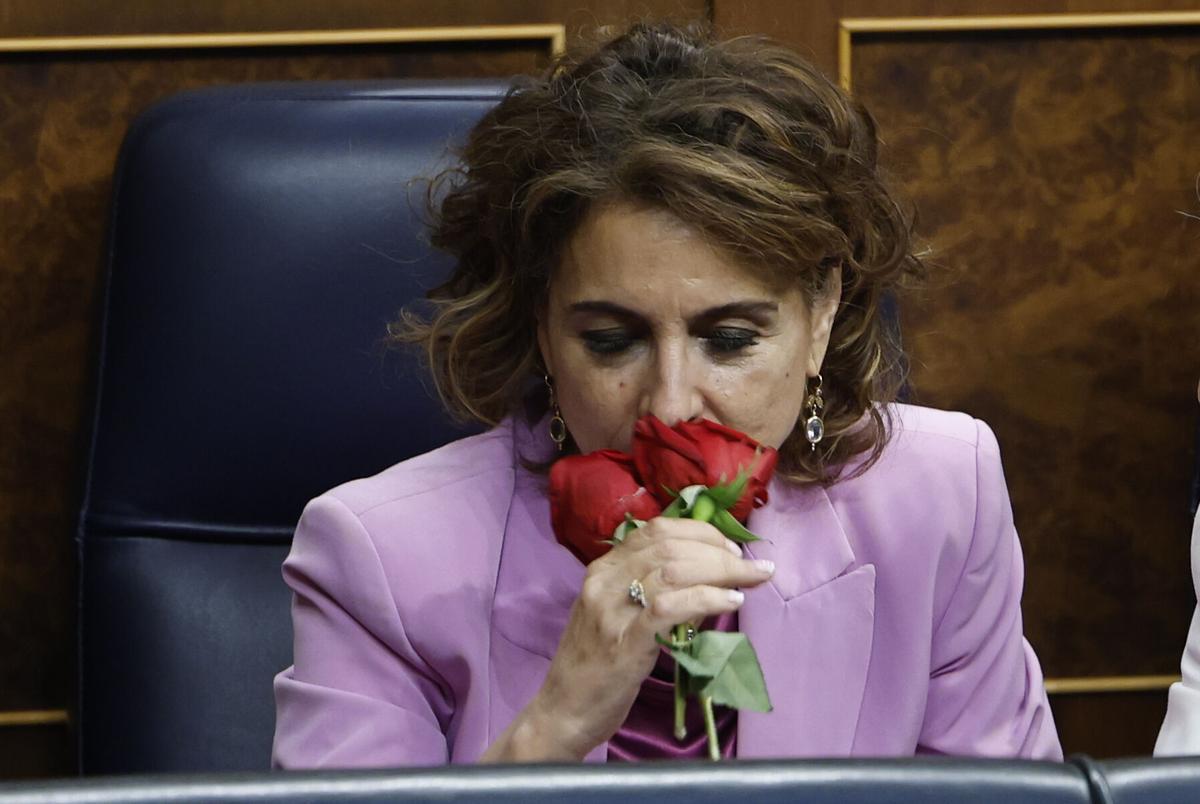 La vicepresidenta primera y ministra de Hacienda, María Jesús Montero, huele un par de rosas que le ha regalado el diputado socialista Antidio Fagúndez, durante el pleno en el Congreso de los Diputados, este jueves. EFE/ Chema Moya. añade txto y vídeo