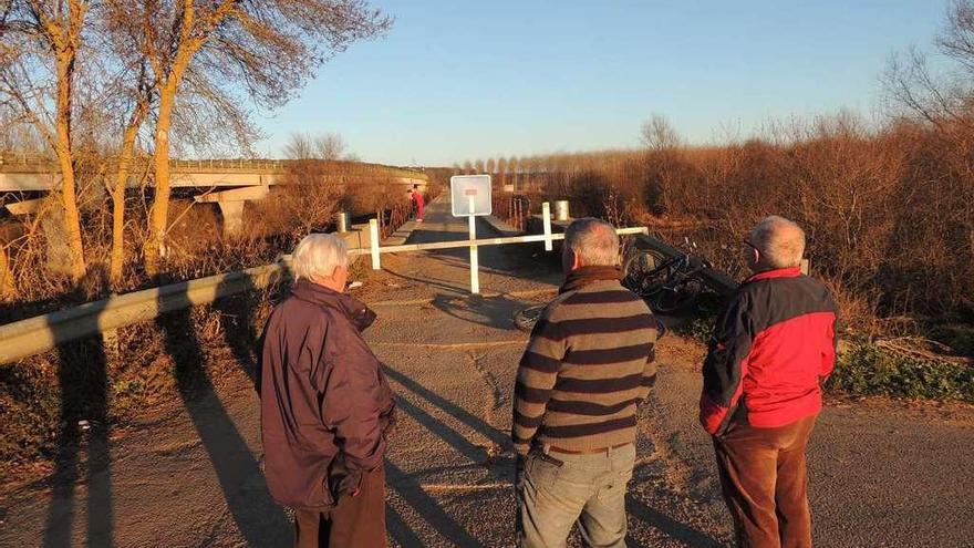 Tres vecinos observan el viejo puente sobre el Órbigo, en Manganeses de la Polvorosa.