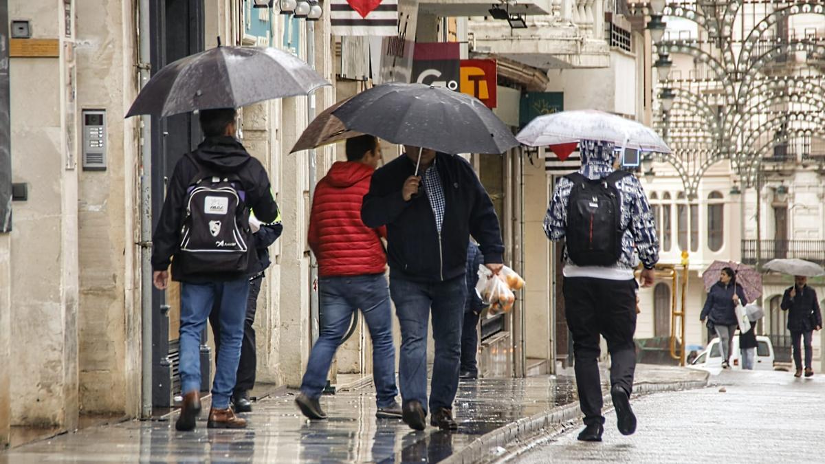 Varias personas resguardándose de la lluvia con sus paraguas en el centro de Alcoy este miércoles.