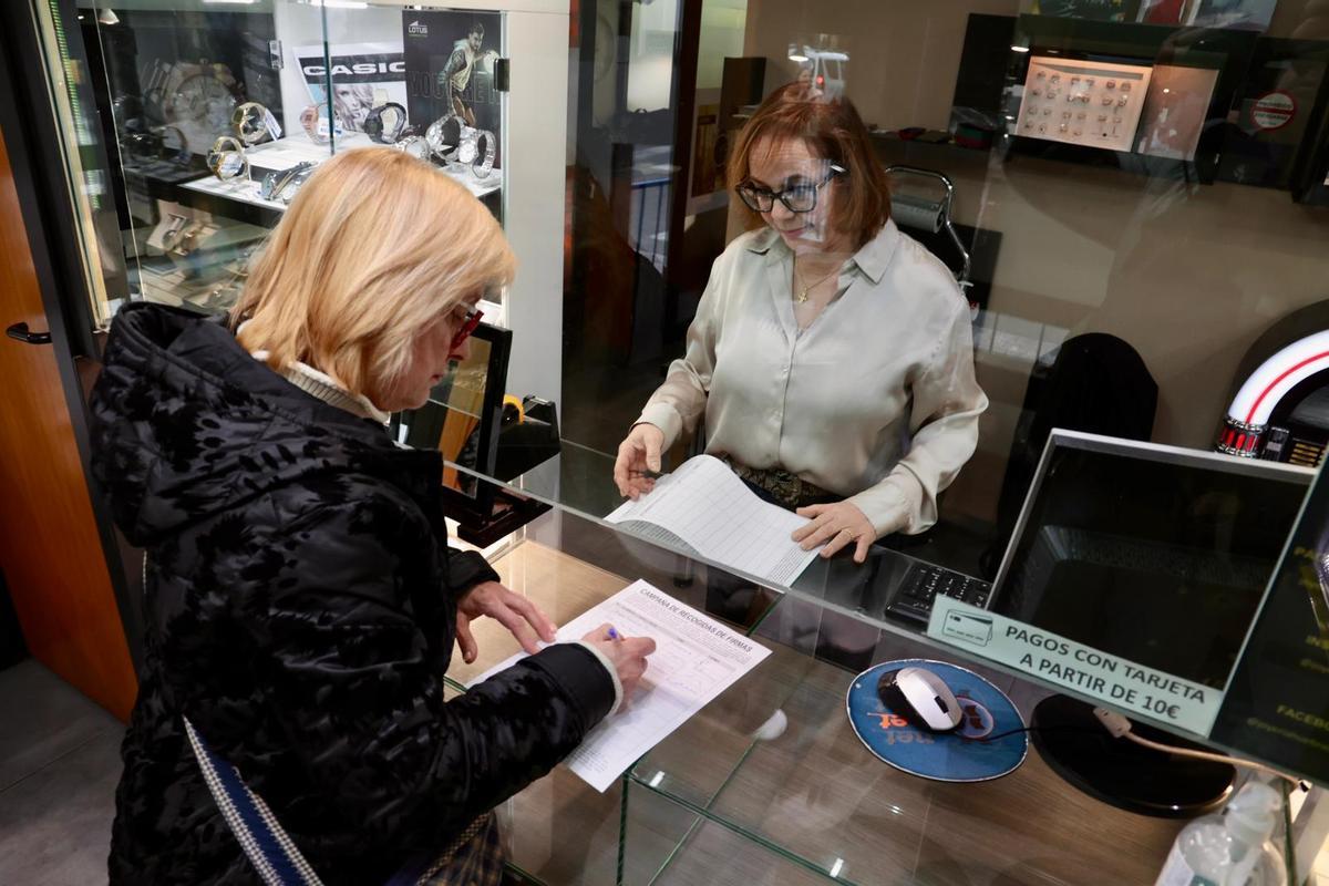 Una mujer firma en uno de los comercios afectados para que los trámites se lleven al extrarradio de la ciudad.