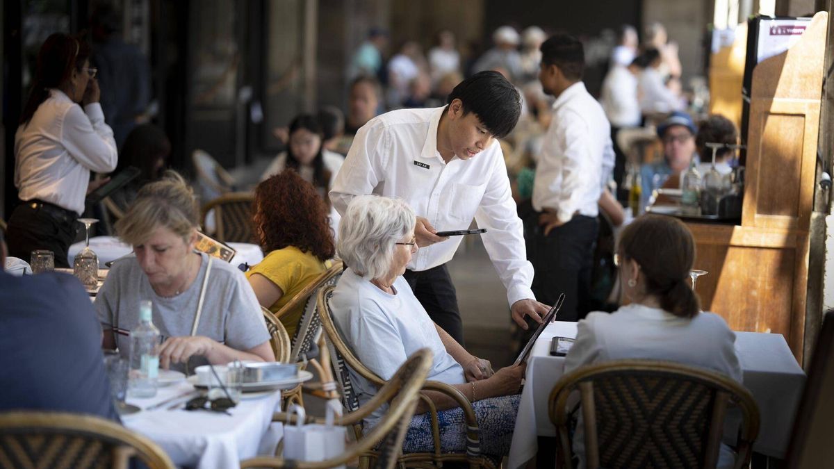 Un camarero atiende a unos clientes en una terraza de la Plaça Reial de Barcelona, este mes de junio.
