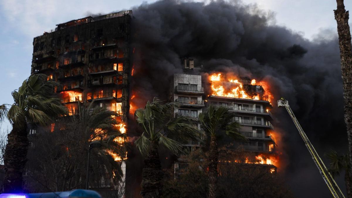 Los dos edificios incendiados el pasado jueves, al anochecer, cuando aún eran pasto de las llamas. A la derecha, los bomberos se acercan con una autoescalera.