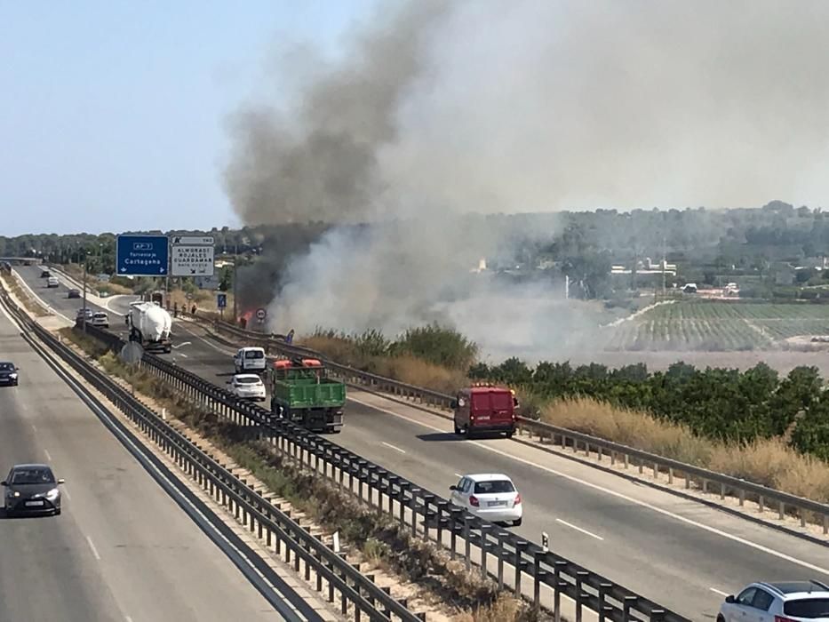 Los bomberos extinguen un incendio de matorral junto a la AP-7