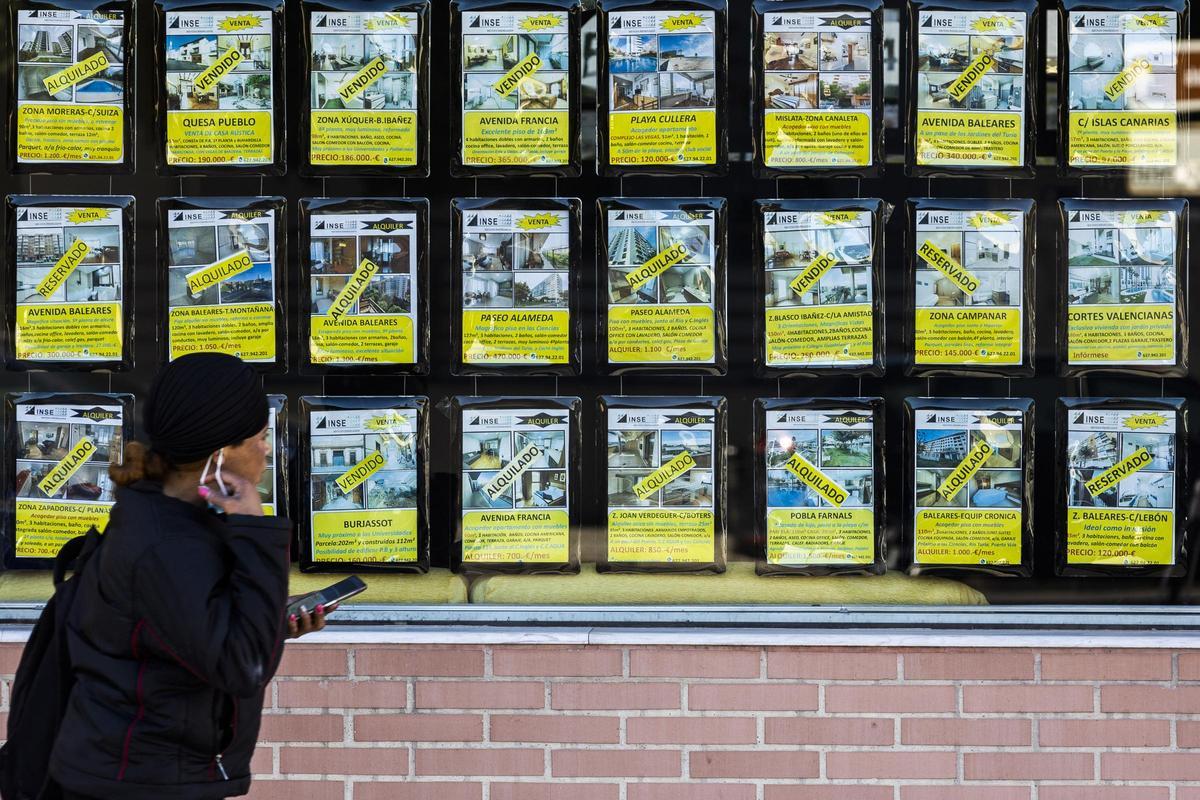 Una mujer pasa ante el escaparate de una vivienda de València.