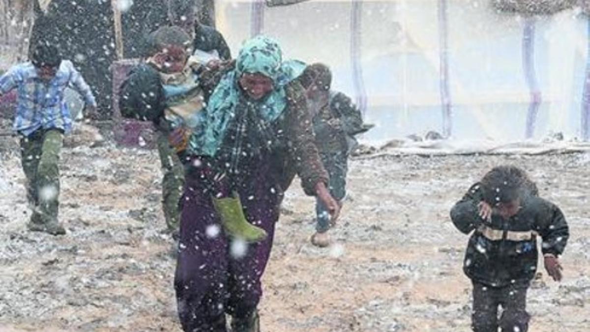 Una familia siria corre bajo la nieve en un campo de refugiados en el Líbano.