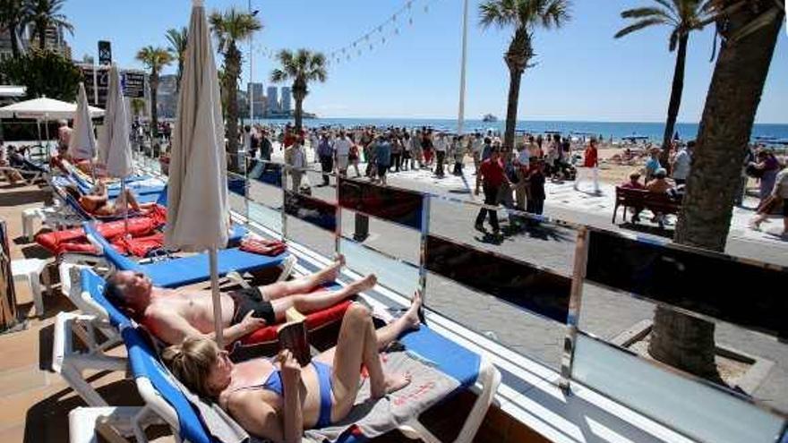 Turistas tomando el sol en la terraza de un hotel en primera línea de playa en Benidorm.