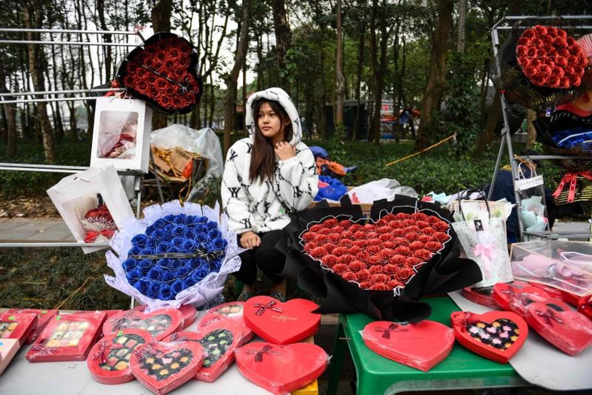 Una vendedora que vende ramos de flores y chocolates para el Día de San Valentín espera a los clientes en su puesto callejero en Hanoi