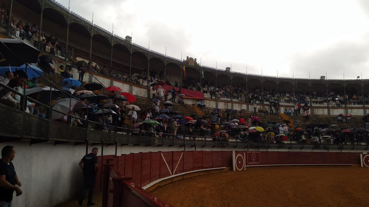 Los espectadores, cubiertos con paraguas, esperan la decisión sobre la corrida de rejones, que fue finalmente suspendida en Priego de Córdoba.