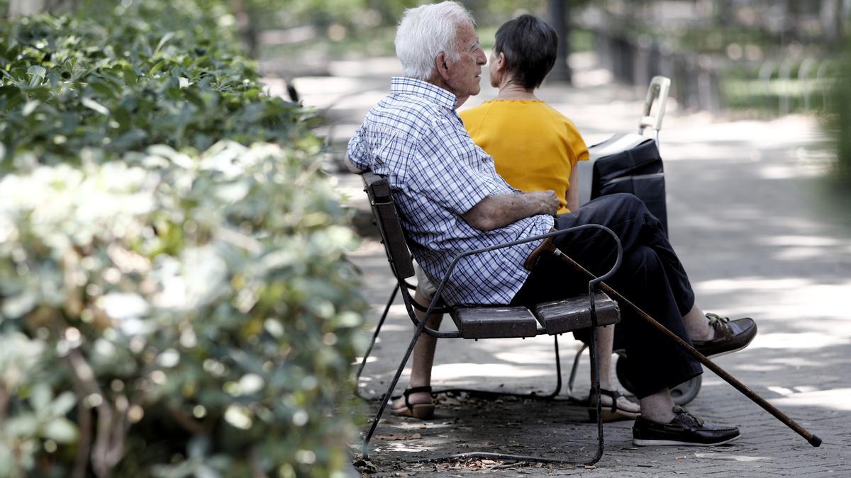 Un pensionista descansa en un banco de un parque.