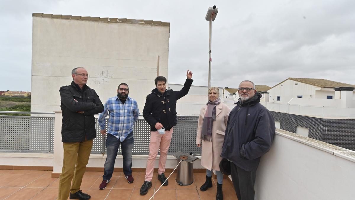 Cinco integrantes de la asociación de vecinos de la playa, junto al sonómetro con el que miden el nivel de ruido del polígono a través de un sonómetro instalado en una terraza de una vivienda.