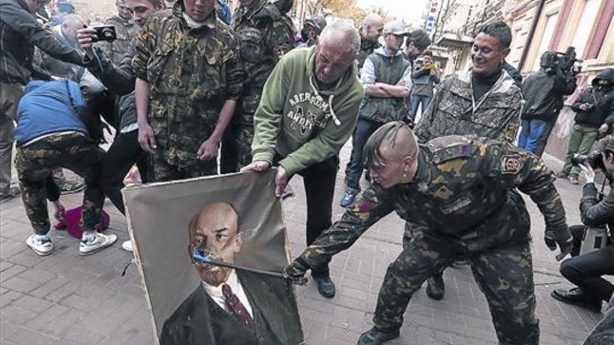 Un miembro de las fuerzas de autodefensa de Maidán aporrea un retrato de Lenin, el miércoles, en Kiev.