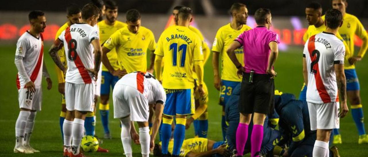 Los jugadores del Rayo y de la UD rodean a Cedrés, tendido en el césped y atendido por el médico y el fisio, el domingo.