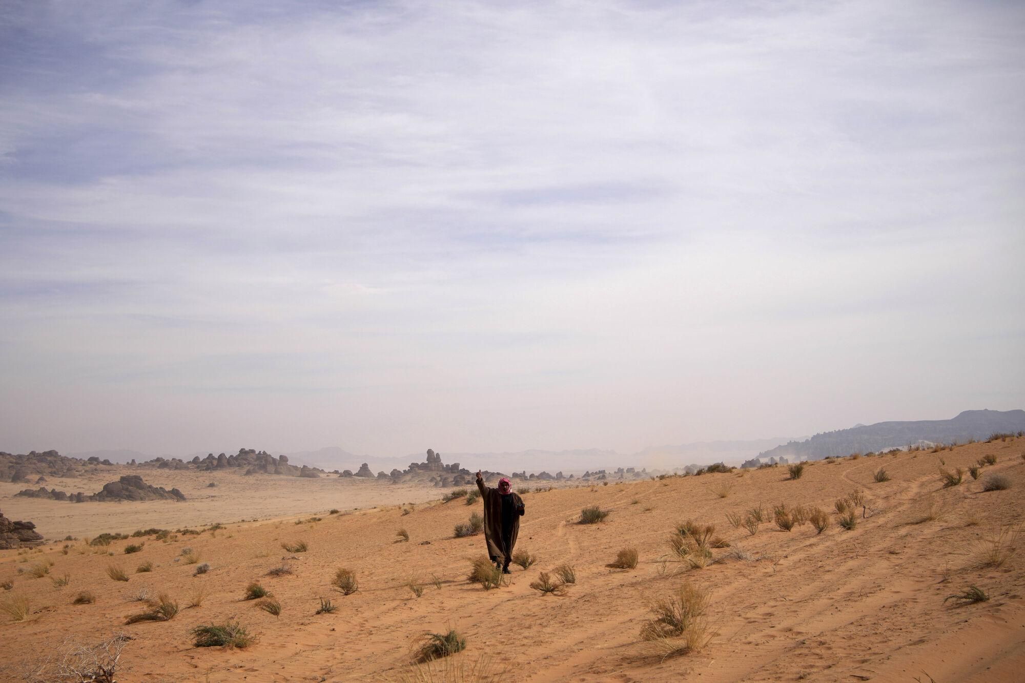 A man waves as he watches the drivers during the fifth stage of the Dakar Rally between Alula and Hail, Saudi Arabia, Thursday, Jan. 9, 2025. (AP Photo/Christophe Ena). EDITORIAL USE ONLY / ONLY ITALY AND SPAIN
