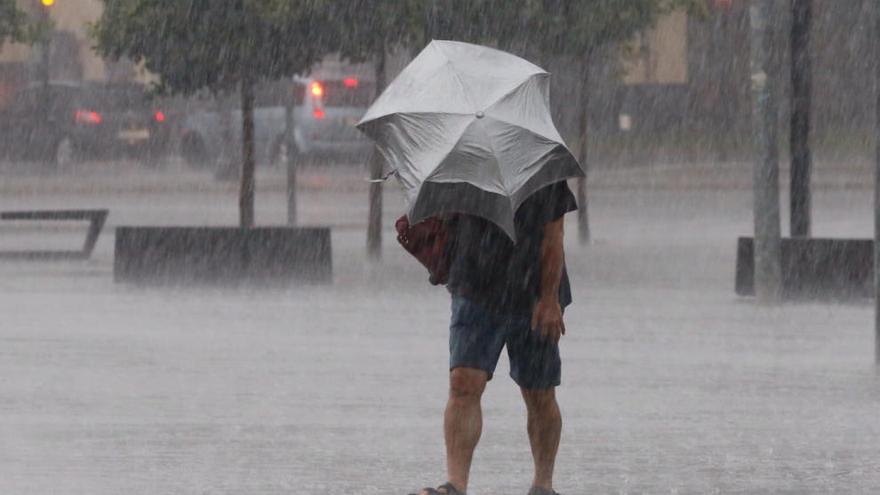 Un hombre intenta guarecerse durante la última tormenta en Valencia.