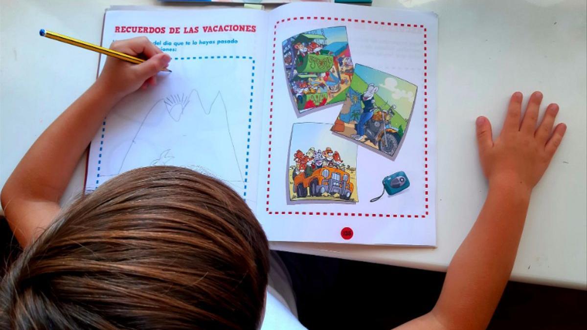Un niño comenta los recuerdos de sus vacaciones en un cuaderno de verano.
