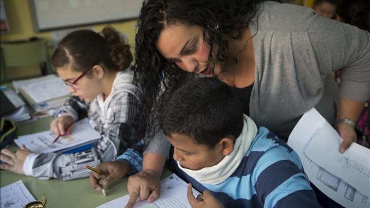 Una madre del colegio Joaquim Ruyra de L'Hospitalet ayuda como voluntaria a un alumno de sexto de primaria en una clase de Matemáticas.