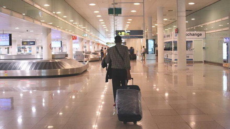 Un viatger caminant amb maletes a la zona d&#039;arribades de la T1 a l&#039;aerport del Prat