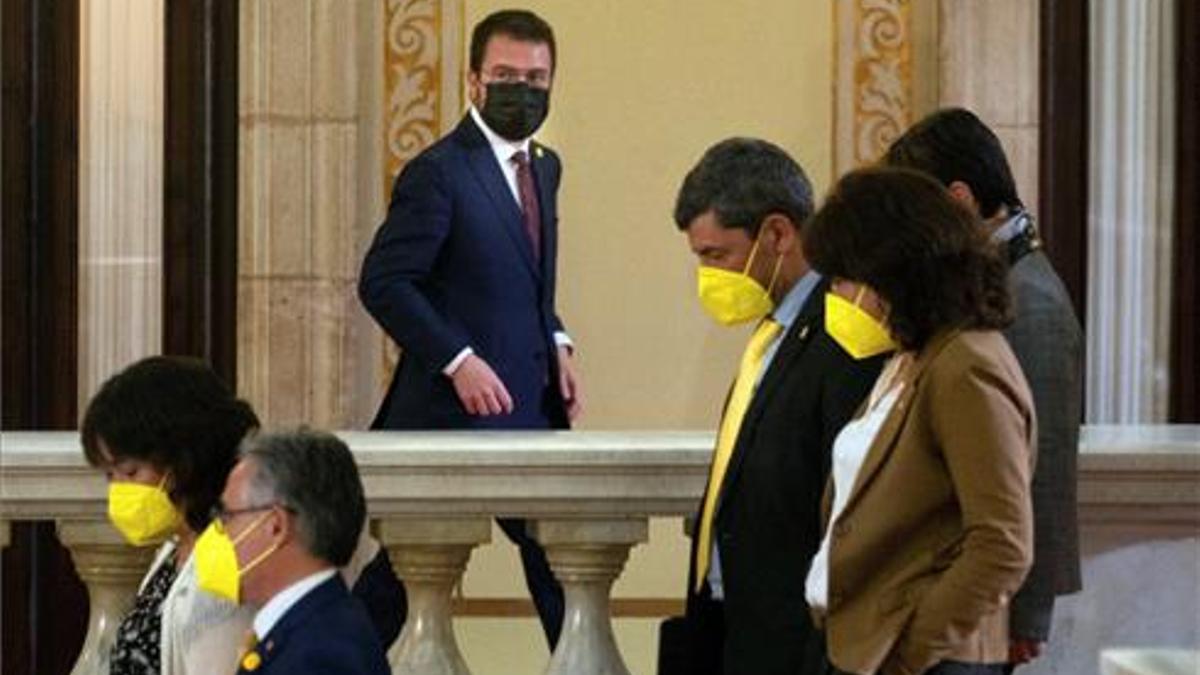 El candidato de ERC, Pere Aragonés, junto a varios diputados de JxCat, en los pasillos del Parlament durante un receso del debate de investidura del nuevo presidente de la Generalitat.