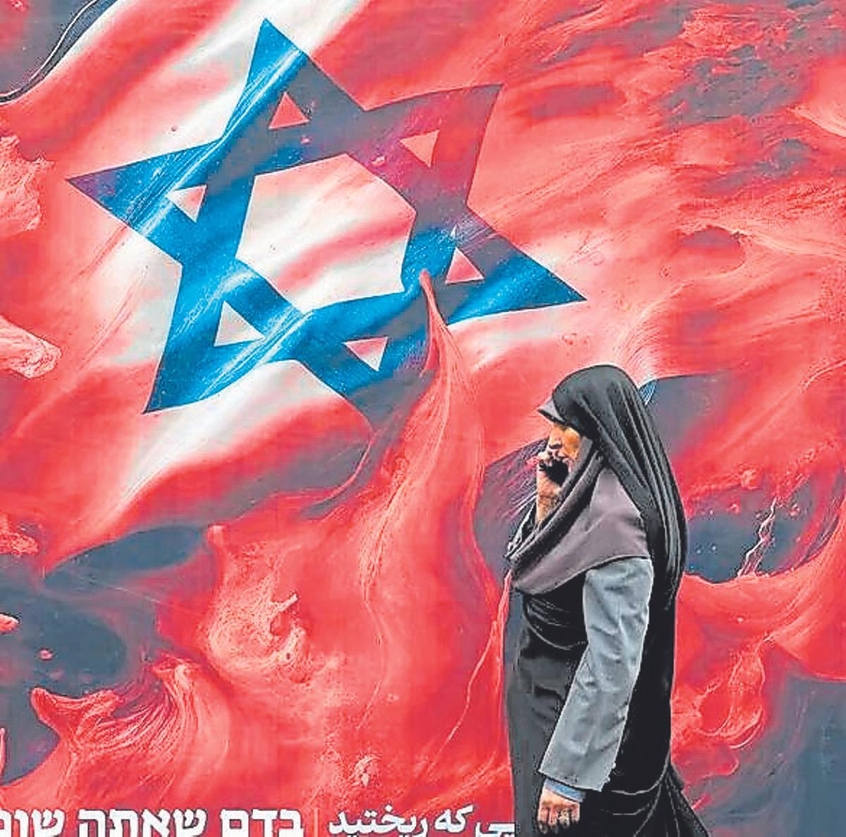 Una mujer iraní camina frente a un mural en contra de Israel en Teherán.