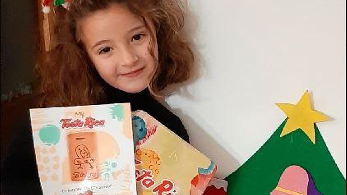 La pequeña Ariadna, que estudia en el colegio Cervantes de Vila-real, posa junto a la caja personalizada de TostaRica con su dibujo de un extraterrestre.
