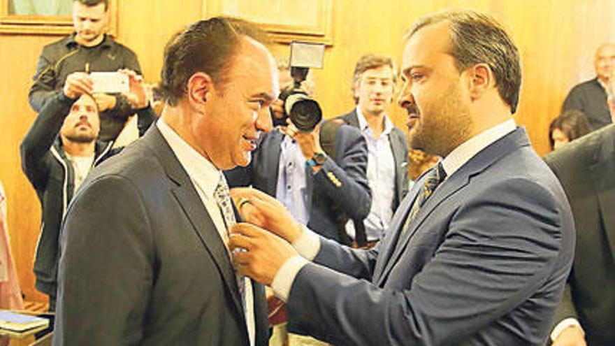 Rafael Cuiña coloca la corbata a José Crespo el día de su toma de posesión en el salón de plenos, con los retratos de este y de Xosé Cuiña al fondo.  // Bernabé/Gutier