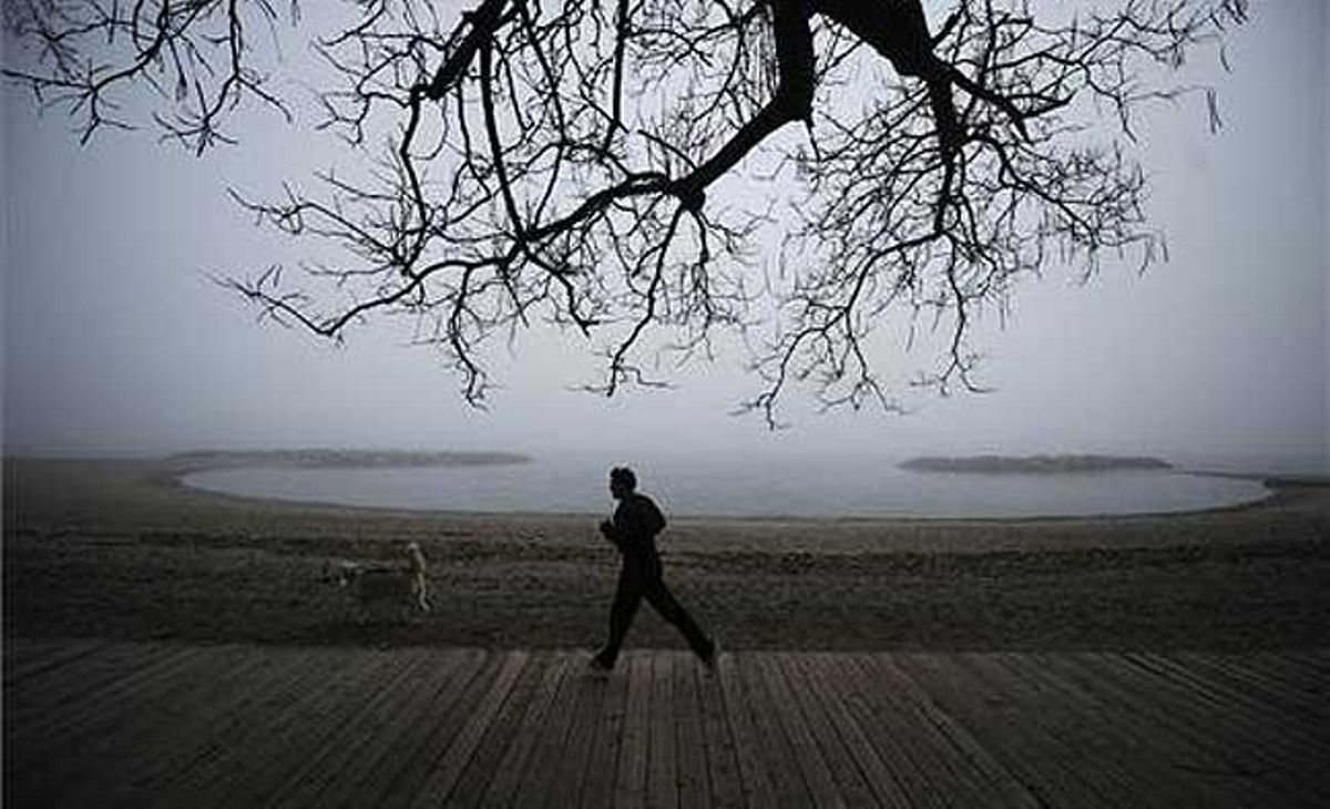 Un home corre amb el seu gos en un matí boirós a la vora del llac Ontario, a Toronto (Canadà).