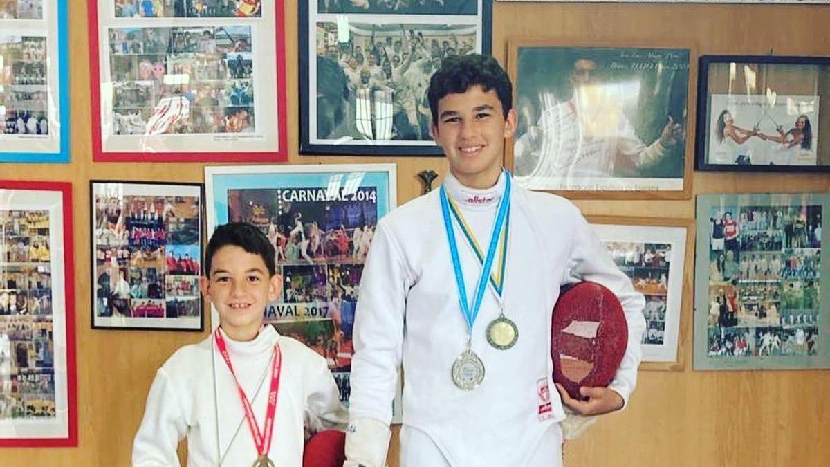 Manu, a la izquierda y José, los hermanos Falcón Paiser, posan orgullosos con sus medallas y sus equipaciones de competición en el Club La Sala de Armas