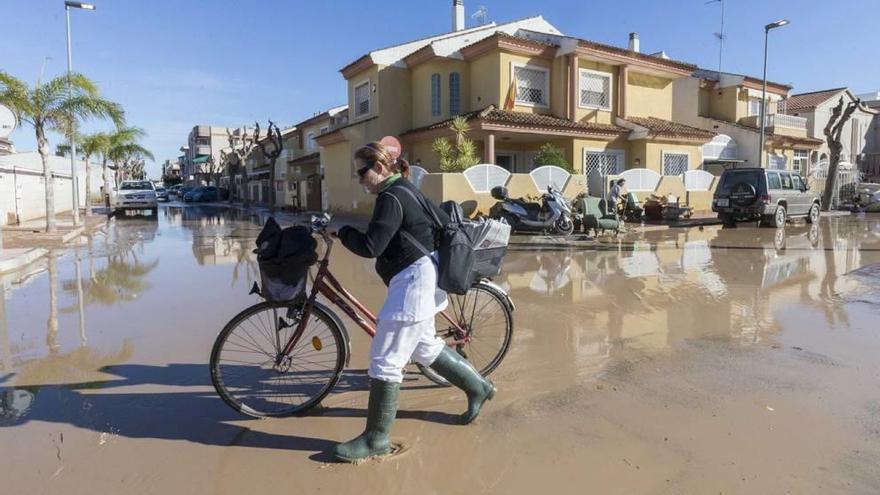 Una mujer pasa con su bicicleta por una calle de Los Alcázares inundada en diciembre de 2016.