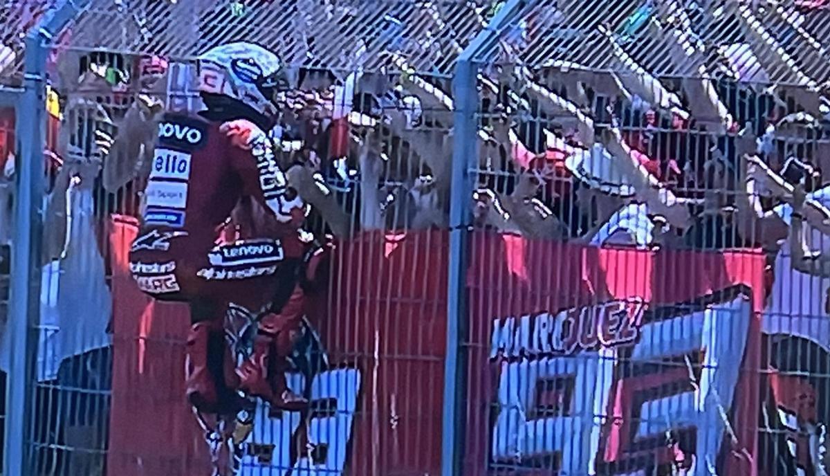 Marc Márquez (Ducati) trepa para saludar y celebrar su victoria 101 con sus fans en Brno.