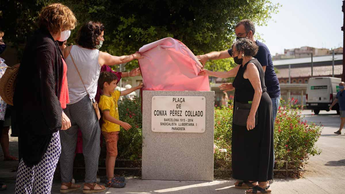 Llum Ventura, emocionada, ayuda a Jordi Rabassa, ambos a la derecha, a descubrir la placa que da nombre a la plaza frente al mercado de Sant Antoni.